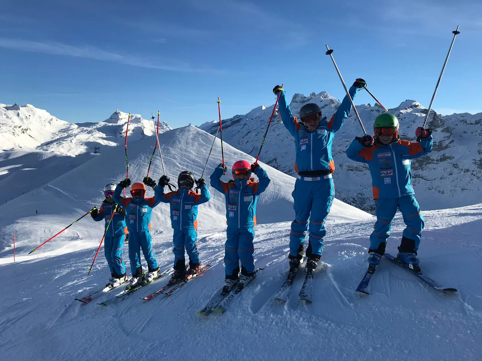 Skikurs-Gruppe mit Kindern im Schnee, alle in einheitlicher Skischul-Bekleidung